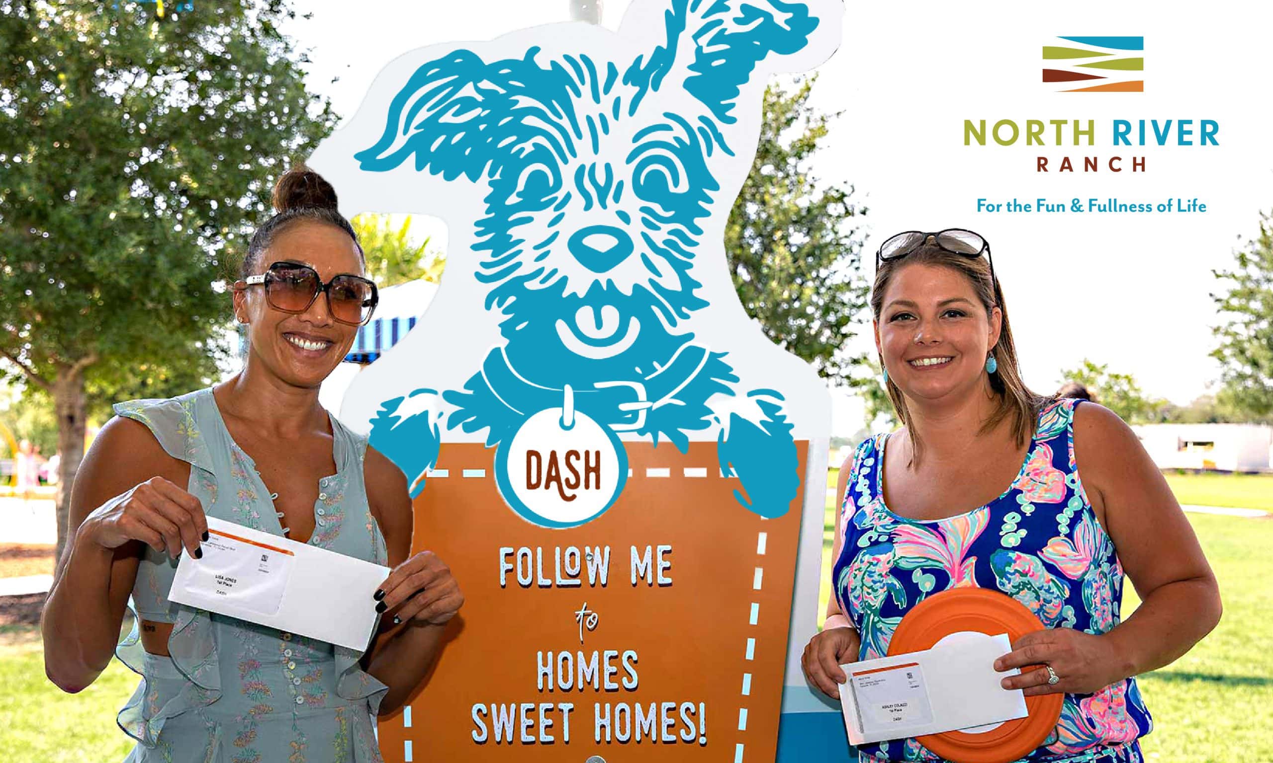 Two female contest winners standing in front of a giant cutout of of an illustrated dog. THe cut out reads. 